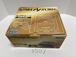 Console Sega Saturn en bon état avec manette grise, manuel et boîte testée.